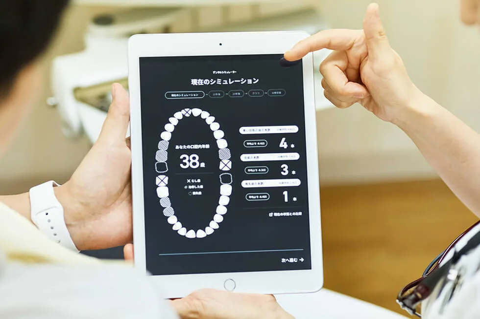 タブレットに表示したシミュレーション結果を指さしながら患者さんに説明している様子
