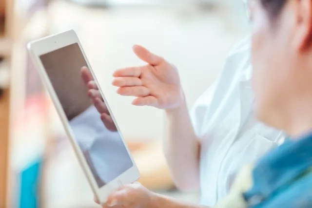 タブレットを見せながら患者さんと話している歯科スタッフ